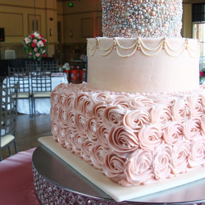Closed Shell Tip number 2D makes beautiful buttercream rosettes on cakes for all events.  This cake shows soft pink rosettes on the bottom tier.