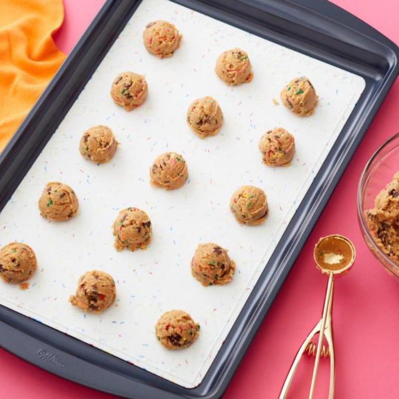 Chocolate chip cookies on confetti fun white silicone baking mat in cookie baking sheet